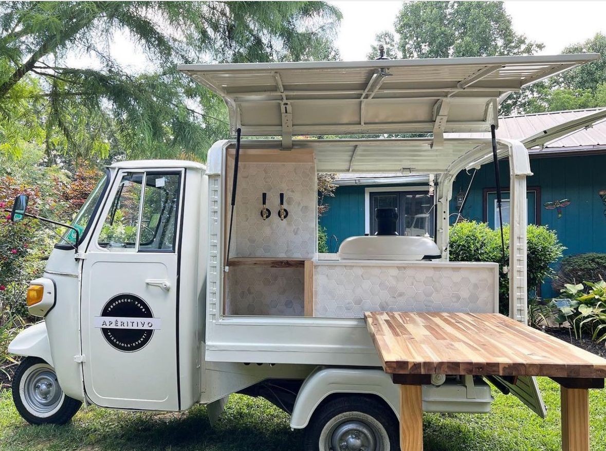 Open food truck parked outside a house, with a wooden counter and taps.